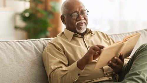 older man reviewing a book on the couch