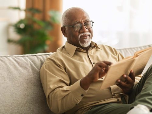 older man reviewing a book on the couch